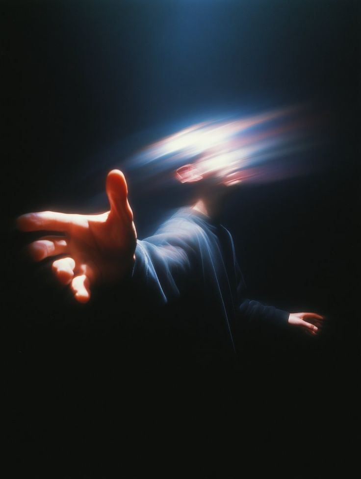 Person with outstretched hand, light radiating from their head, as if reaching out with glowing energy.